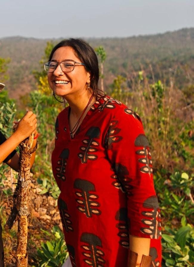 Pallavi in red, laughing in the field