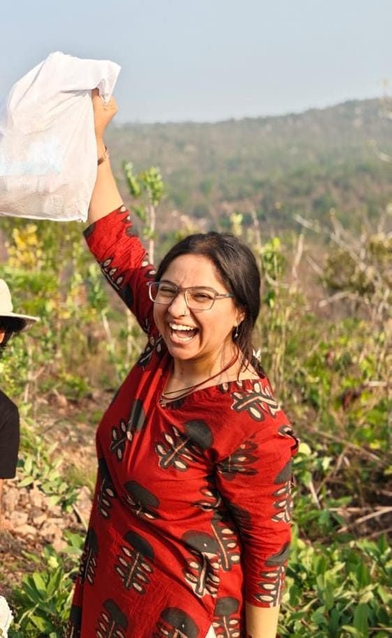 Pallavi holding a paper high on a hillside