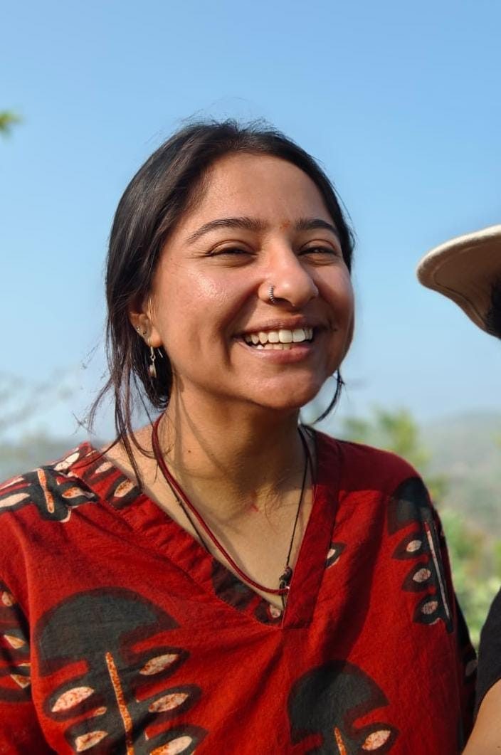 Pallavi laughing outdoors on a hillside